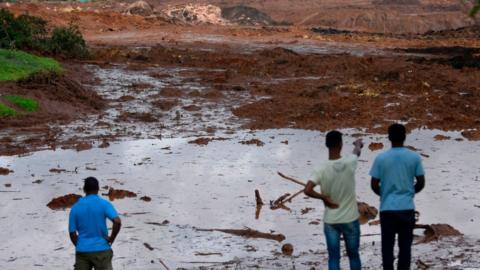 People survey the damage after the dam burst in Brazil