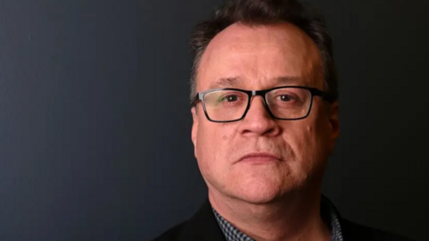 Doctor Who showrunner Russell T Davies wears spectacles against a dark background