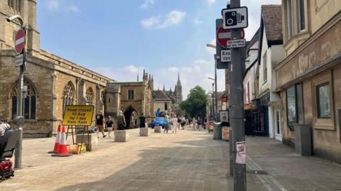 A traffic camera road sign on a grey lamp post on the street off Cowgate with the Cathedral in the background 