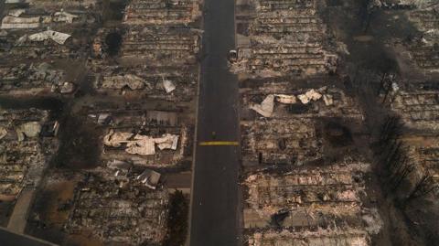 A person walks past gutted homes in the Medford, Oregon