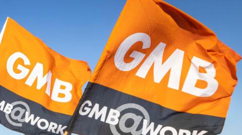 Two orange and grey GMB Union flags with white writing on them.