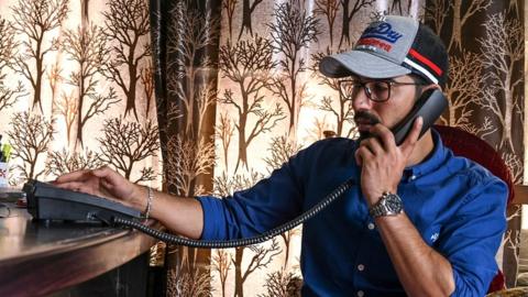 A Kashmiri Muslim talks on a landline phone in Srinagar on 17 August 2019