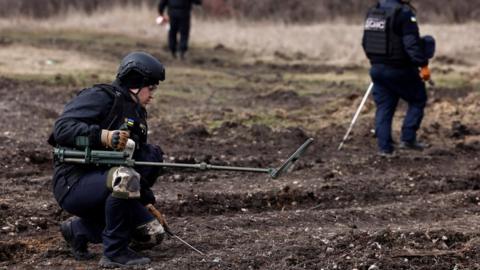 Members of the de-mining department of the Ukrainian Emergency Services survey an area of farmland and electric power lines for land mines and other unexploded ordnance for electricians to access power towers damaged by Russian strikes in order to repair them, amid Russia's invasion of Ukraine, in Korovii Yar, in the Eastern Donetsk region, Ukraine, March 20, 2023.