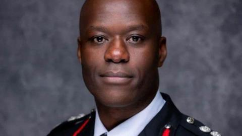 A man with a shaved head is looking at the camera. He is wearing a senior fire officer's uniform.