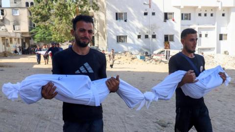 Relatives carry the covered bodies of Palestinian children Saker Sukar, 3, and Layan Sukar, 4, in the grounds of al-Shifa hospital, Gaza City (23 September 2025)