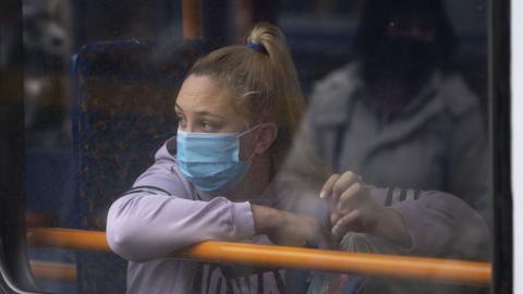 A woman looks out of the window of a bus