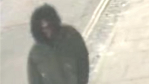 CCTV image of person wearing parka-style coat with hood up