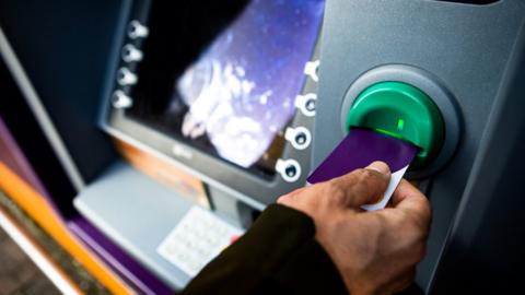 Woman using card in ATM machine