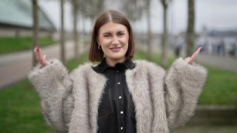 BBC's Eve Beattie looks at the camera with her hands up in the air and a confused expression