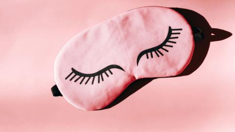 A pink sleep mast with closed eyes drawn on it. 