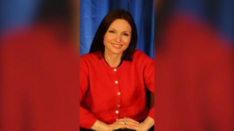 Sophie Ellis-Bextor has dark hair and is wearing a red cardigan.