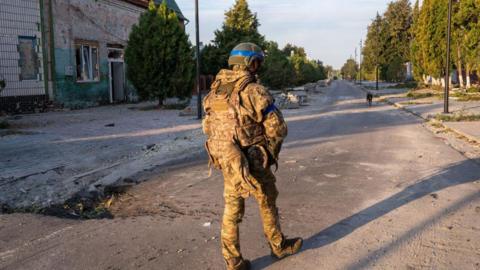 A Ukrainian soldier walks through a town in Russia's Kursk region.