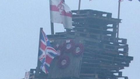 Flags and poppy wreaths on a bonfire in Creggan in 2023