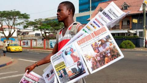 A man sells newspapers with headlines featuring the recent presidential elections on December 29, 2017 on a roadside in Monrovia.