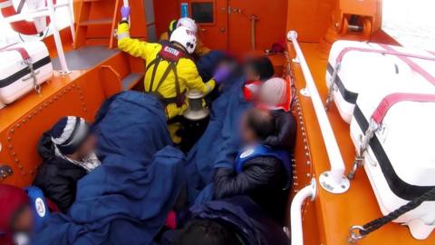 A dinghy full of migrants being rescued by the RNLI in the English Channel.
