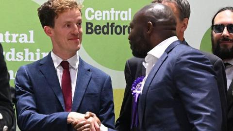Conservative Party candidate Festus Akinbusoye (C) shakes hands with Labour Party candidate Alistair Strathern (L
