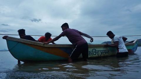 Fishermen bringing a boat to shore