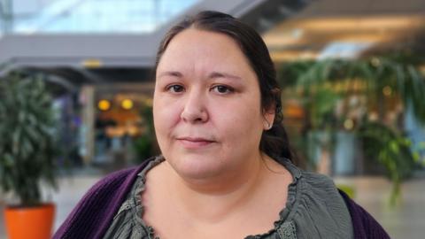 Beth Jones looking at the camera. She is wearing a purple cardigan over a grey top.