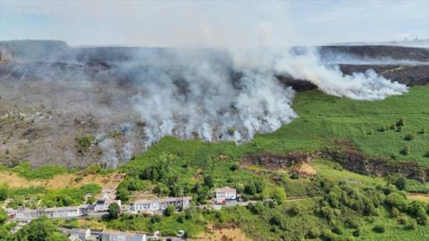 mountain greenery with thick smoke in background.