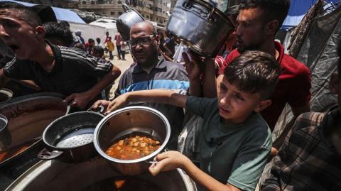 Palestinians wait in line to receive hot meals distributed by charity organizations while Israel's destructive attacks continue on 7 June, 2025.