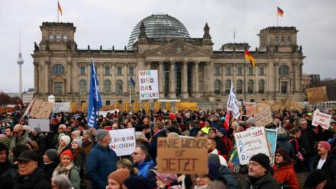 Dozens of protesters gathered outside Germany's parliament holding up signs. 