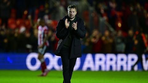 Plymouth Argyle head coach Tom Cleverley claps the fans as he walks across the pitch after defeat.