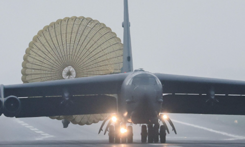 B53 with lights on taking off on grey day on runway. 
