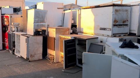An assortment of unused fridges, stacked on top of each other. A variety of cables are strewn across the image.