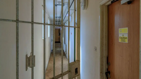 An open gate and a door with a sign saying "caution: uneven surface" at Campsfield House.