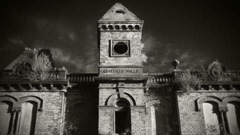 A black and white slightly eerie image of the brick front of the Rosefield Mills building