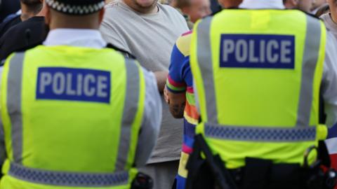 The backs of two policemen in high vis.