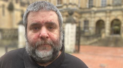 Barry O'Sullivan, who has grey, short hair and a grey, short beard, stood in front of Reading Crown Court. He is wearing a black T-shirt.
