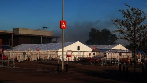 Smoke billowing from the side of a large supermarket