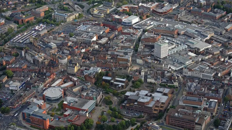 An aerial view of the city. Buildings, roads, office and car parks are visible.