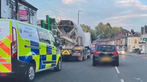 An emergency vehicle parked on a Birmingham street behind a concrete mixer