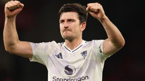 Manchester United player Harry Maguire with his fists raised in celebration to fans after a win