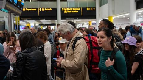 People wait near check-in desks at Gatwick Airport