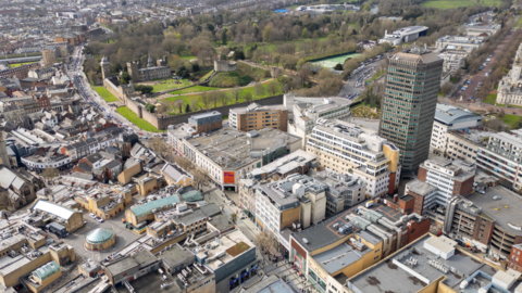 A drone image of Cardiff from above. It shows Queen St and Castle St, with Cardiff castle and Bute park in the background.