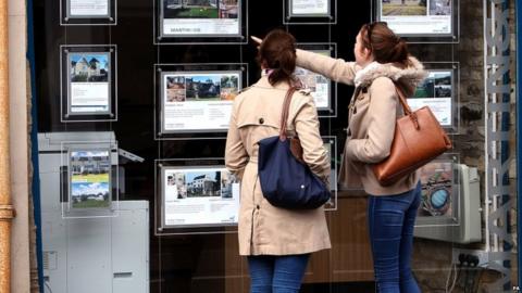 Women look in estate agent window