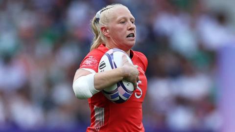 Heather Cowell, wearing Great Britain's red jersey, runs with the ball during a game against Ireland at the Paris Olympics in 2024.