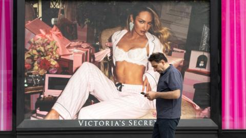 A man walks in front of a Victoria's Secret store front