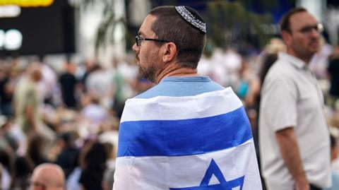 A man wearing a kippah draped in an Israeli flag