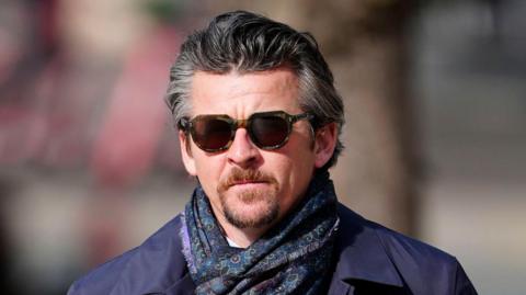 Joey Barton, wearing dark sunglasses, walking outside the court