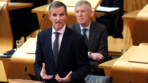 Liam McArthur talks in the Scottish Parliament