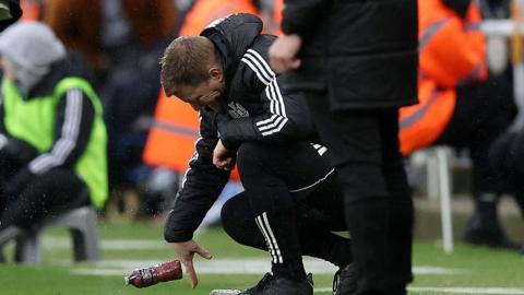 Newcastle manager Eddie Howe throws a bottle on the ground after Everton score