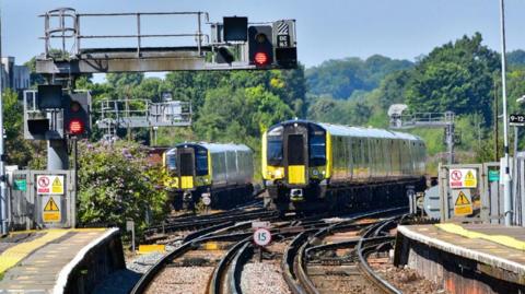 Two South Western Railway trains approach a station.