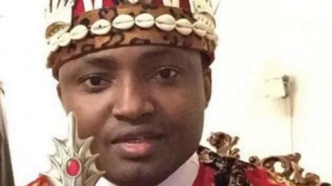 Simon Ekpa dressed in Igbo king traditional attire holding a staff