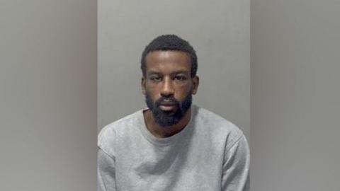 Nathaniel Sereaton: A man with black hair and a black beard wear a grey, round-necked T-shirt