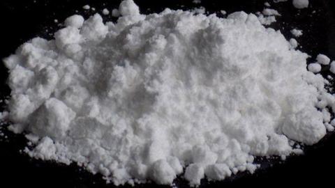 A white powder in a pile on a black surface. 