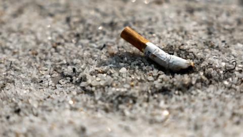 A discarded cigarette butt on some sand.